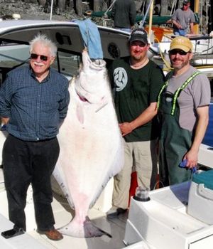Ryley Fee, center, of Woodinville stands with a 180-pound halibut he caught several years ago in the eastern Strait of Juan de Fuca, along with fishing partners Brian Fleming, left, and Marv Fleming.