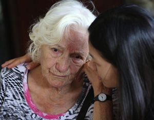 A worker consoles Elizabeth, a patient from Switzerland, at Baan Kamlangchay center, where the monthly cost of care is a third of basic institutional care in Switzerland. <br/>