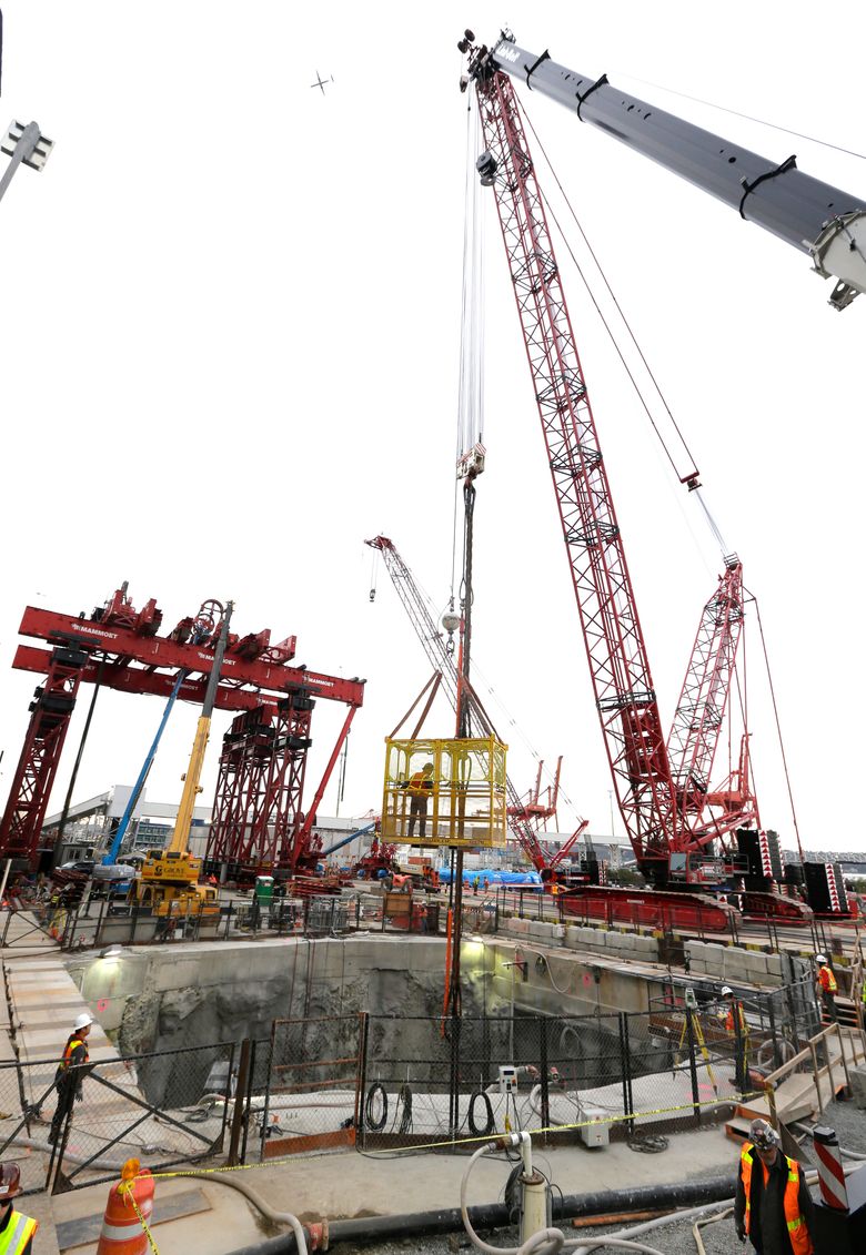 A crane lowers a worker into a 120-foot deep access pit Thursday, March 19, 2015, as preparations are made to lift a 270-ton section of the front shield of “Bertha,” the massive tunnel boring machine currently stopped underground for repairs near downtown Seattle. The machine was digging a 1.7-mile highway tunnel as a replacement for the Alaskan Way Viaduct. (AP Photo/Ted S. Warren, Pool)