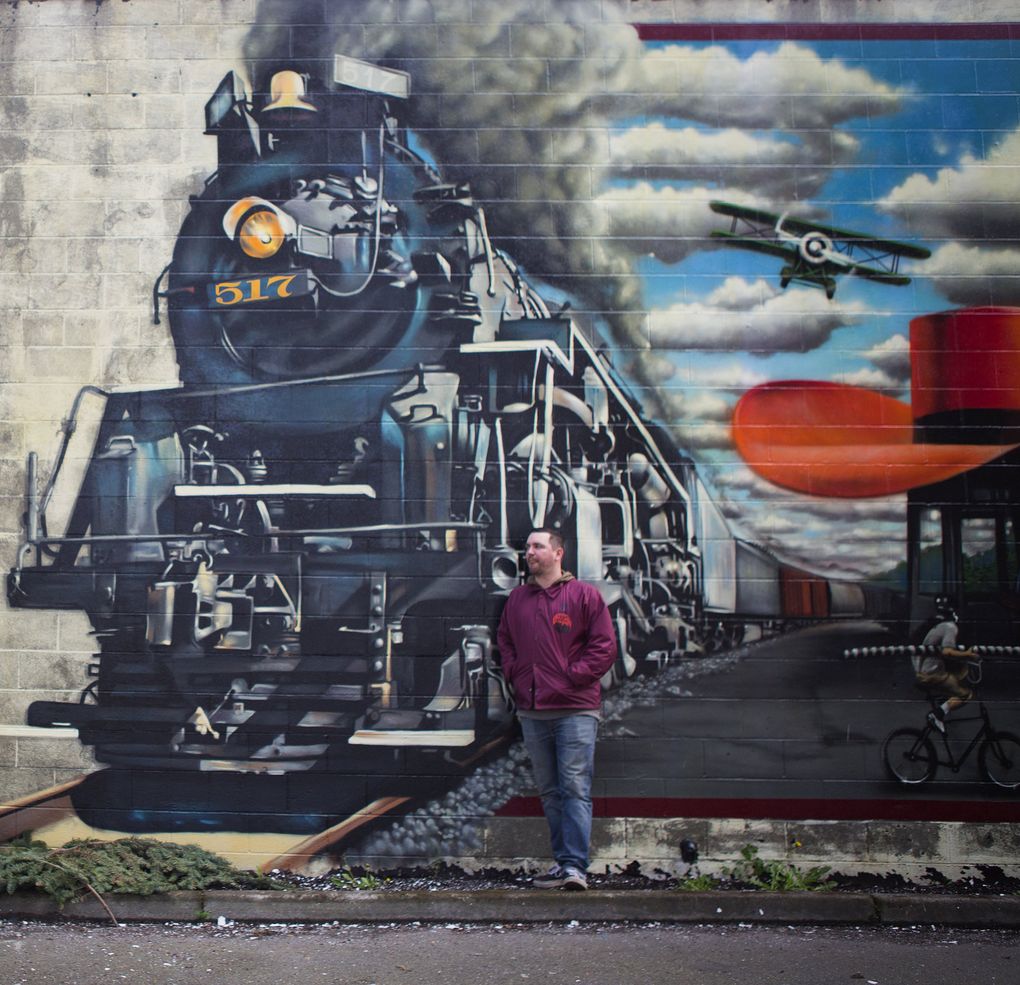 Joey Nix stands by his mural at Brass Tacks in Georgetown. The Old Sage in Capitol Hill also bears his art. (Lindsey Wasson/The Seattle Times)