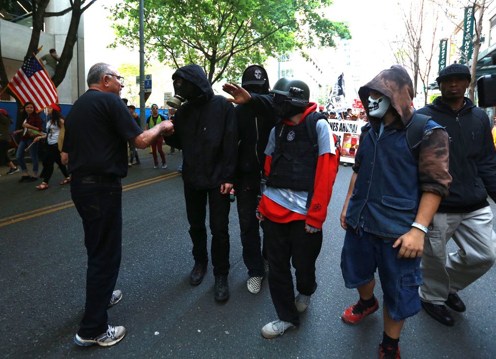 Immigration marchers politely ask anarchist-styled protesters to leave the front of the march on 7th Avenue during the annual May Day march and rally for immigrants and workers’ rights. (Bettina Hansen / The Seattle Times)