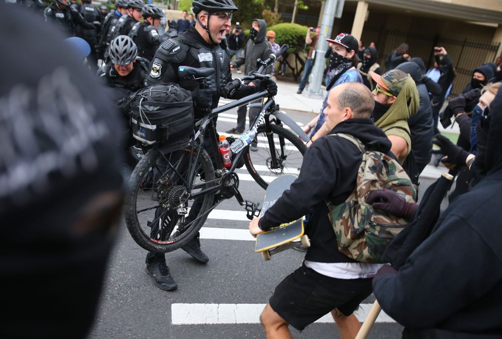 Police push back demonstrators, begin using mace and flash bang grenades and tend to an injured officer in Capitol Hill on Broadway. (Dean Rutz / The Seattle Times)