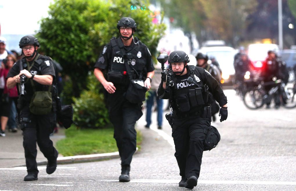 A Seattle police officer uses an air gun to shoot nonlethal bullets at protesters on Olive Way and Melrose Avenue. (Lindsey Wasson / The Seattle Times)