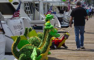 Dragons that will be used on a boat as part of a decoration seem to be checking out a man walking down the dock at the Seattle Yacht Club Friday, May 1, 2015, in Seattle.  Boat owners and yacht club members decorated their boats at the Seattle Yacht Club in preparation for the opening day of boating season tomorrow, May 2, 2015.   “Myths and Monsters” is the theme of the 2015 Opening Day Boating Festivities and parade goers will see boats in full dress as well as decorated boats in “Myths and Monsters” regalia as they parade through the Montlake Cut.  Festivities begin with rowing competitions from local, regional and international athletes and the celebration ends with decorated vessels of all shapes and sizes decorated to the “Myths and Monsters” theme.