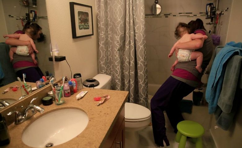 Still wearing her scrubs, Sydney Homeier runs a bath for Helen. She works two 12-hour shifts on the weekends to save money on child care. (Erika Schultz/The Seattle Times)