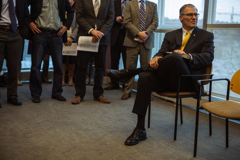 Gov. Jay Inslee listens to another speaker as he waits to release details of his climate plan during a news conference at REI in South Lake Union. (Ellen M. Banner / The Seattle Times, 2014)