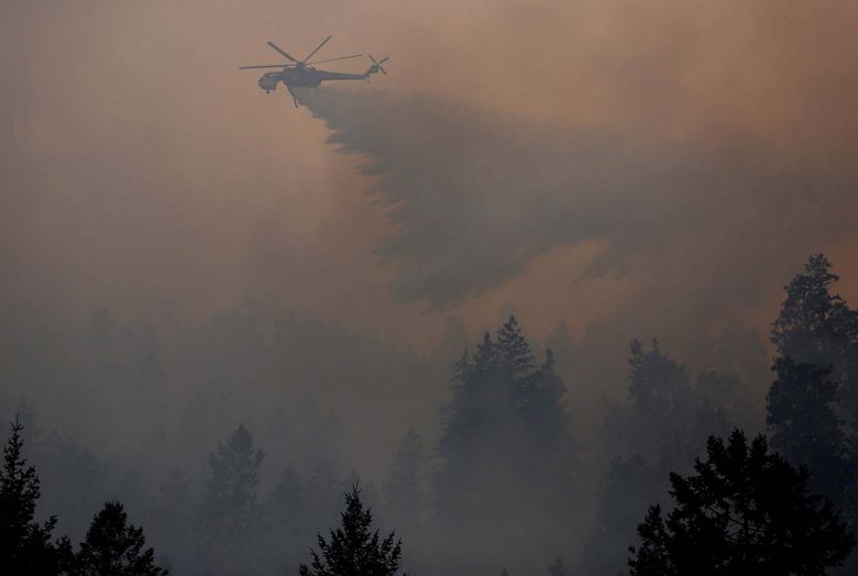 A helicopter drops a load of water Sunday on the First Creek Fire.  (Sy Bean / The Seattle Times)