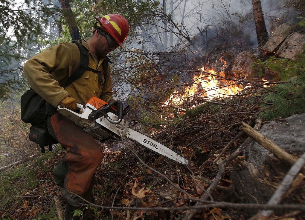 Adam Jordan from Oregon heads back uphill after clearing brush Sunday at the First Creek Fire in the Lake Chelan State Park. (Sy Bean / The Seattle Times)