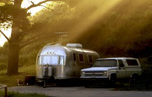 Early morning light beams through the trees, illuminating a campsite with a classic Airstream trailer at Montana De Oro State Park, Calif., campground, also known as Islay Creek campground, May 22, 2005. A first-come, first-served, self registration site, it offers outhouses and potable water but no showers. (AP Photo/Los Angeles Times, Ricardo DeArantanha) ** MANDATORY CREDIT **CALOS501