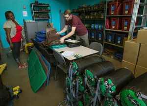 Andrew Pringle of Washington Trails Association (WTA) checks in items returned by group leader Renee Pierce at WTA’s Gear Library in Seattle’s Mount Baker district. (Ellen M. Banner/The Seattle Times)