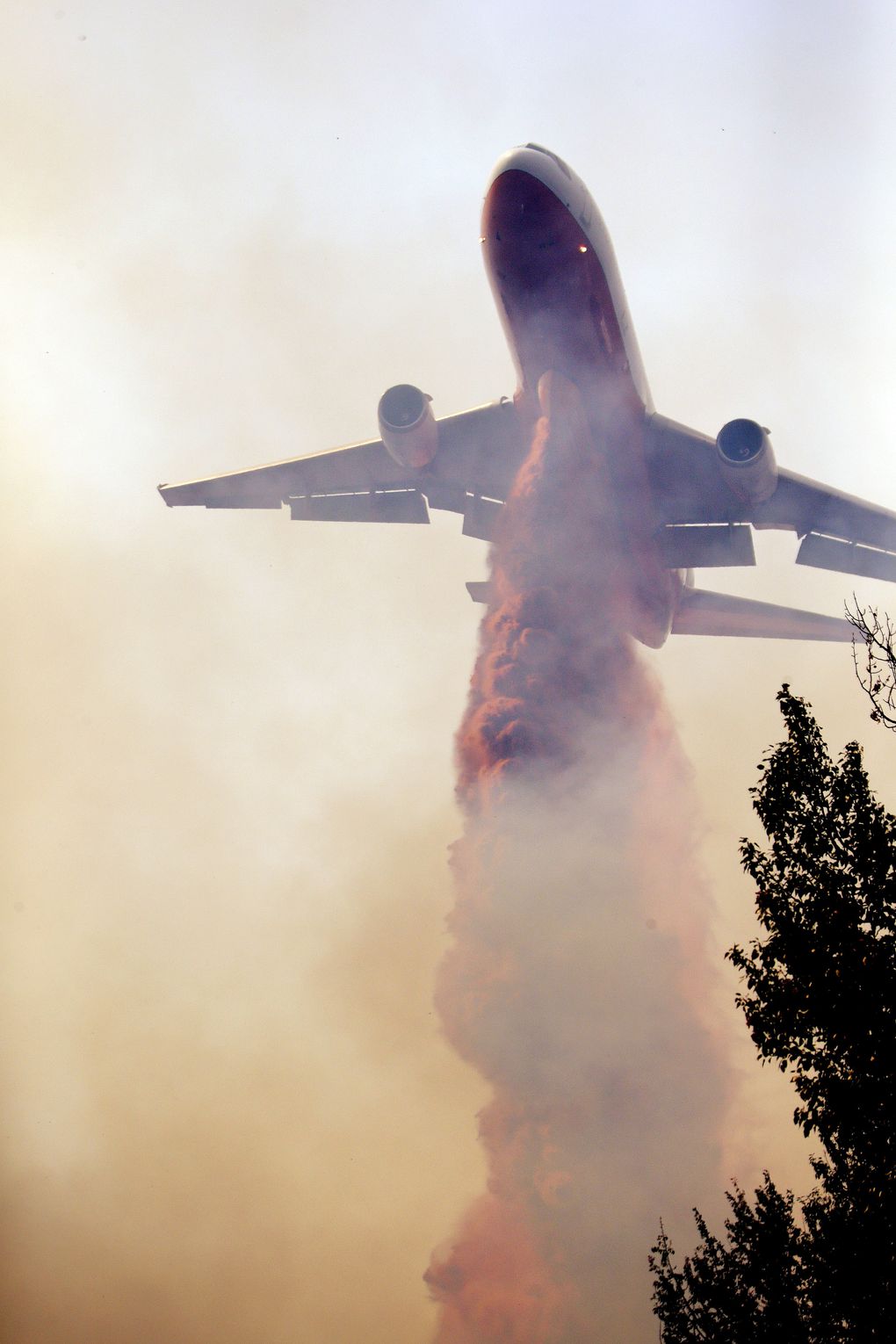 Fire retardant drops from the belly of a DC-10 tanker onto a fire that flared up Thursday afternoon in Twisp. (Elaine Thompson / The Associated Press)