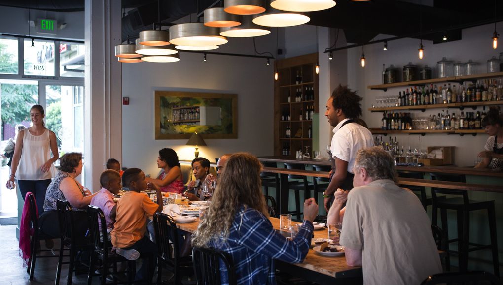 Salare’s main dining room features a 14-seat communal table and bar as well as smaller tables by the windows. (Lindsey Wasson/The Seattle Times)