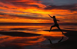A brilliant sunset makes for a fun silhouette picture by jumping between sand bars at Shi Shi Beach on the Olympic Peninsula Friday July 17, 2015.