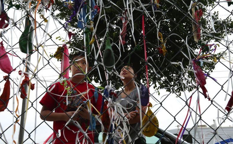 Ribbons and old balloons line the fence in July as Melody Lau and her cousin, Isaac Chau, visit Edith Macefield&#8217;s home. Isaac was visiting from California. (Alan Berner/The Seattle Times)