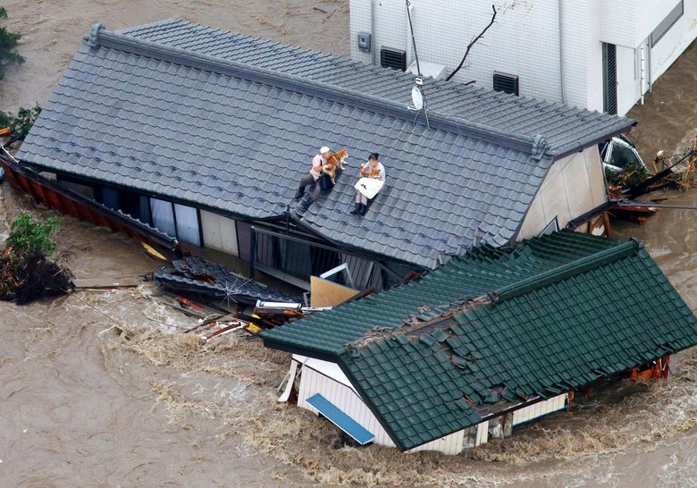 Residents holding dogs wait for help on the roof of their house in the flooded city of  Joso, Japan Thursday.  (Kyodo News via AP) 