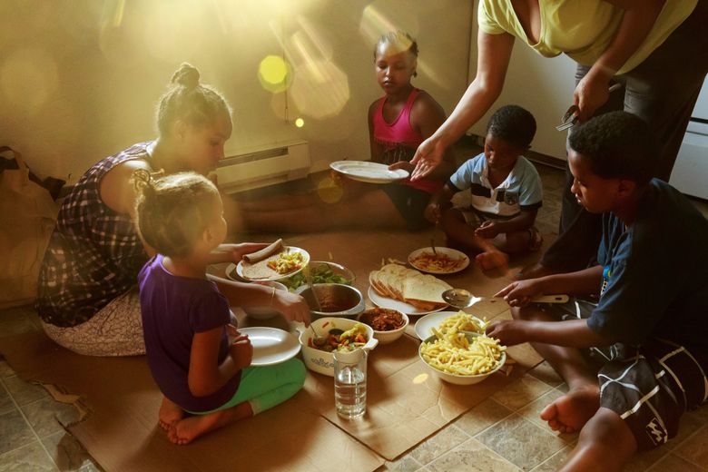 Emebet Amdetsion serves her five children dinner on the floor of their sparsely furnished town house while her husband Wondimu Habtemariam attends ESL classes. The family, diversity visa immigrants from Ethiopia, previously lived in a homeless shelter. (Erika Schultz/The Seattle Times)