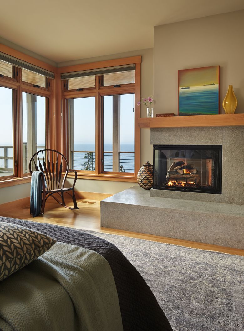 A tall ceiling gives the intimate master bedroom, with a gas fireplace, a grand feel. The room is located on the lower floor, but is flooded with light. All the walls in the home are either this shade of Sherwin Williams 7051 (Analytical Gray) or, in a few spots, a shade darker. (Benjamin Benschneider/The Seattle Times)