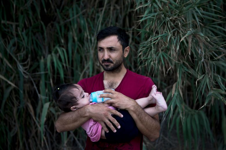 A Syrian refugee feeds milk to his daughter after they arrived on a dinghy, from Turkey to Lesbos island, Greece, Wednesday, Sept. 9, 2015. The head of the European Union’s executive says 22 of the member states should be forced to accept another 120,000 people in need of international protection who have come toward the continent at high risk through Greece, Italy and Hungary. (AP Photo/Petros Giannakouris)