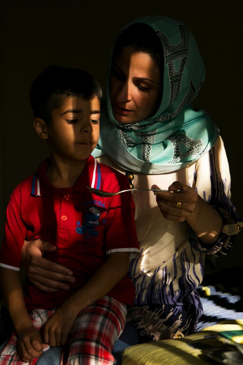 Suhad Kadhim spoons soup to her son Sadk Sudan, 6, after multiple teeth were pulled at a dentist appointment. The family, which fled Iraq and lived in refugee camps before being resettled in Seattle, is not at imminent risk of losing its home, but putting down permanent roots here will be challenging. (Erika Schultz/The Seattle Times)