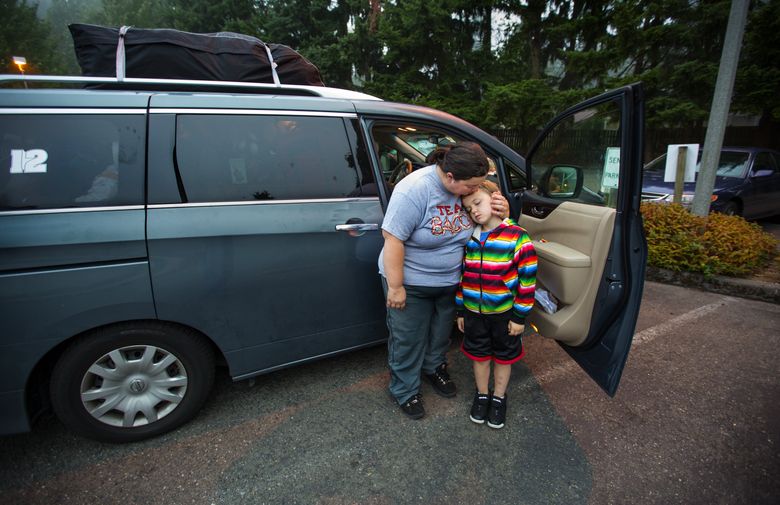 Babette Van Hook helps her son David Johnson, 7, wake up after they slept in their van at Lake Washington United Methodist Church in Kirkland. Babette wakes early and rearranges the van’s contents so she can drive her son to school and herself to work.  (Mike Siegel/The Seattle Times)