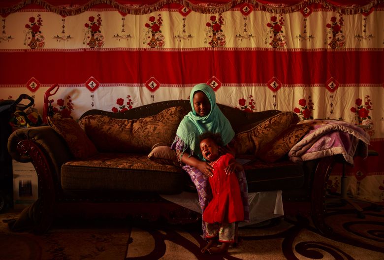 Ayan Rashid, 12, comforts her sister Muna Rashid, 2, inside their apartment in Kent. The Somali Bantu family lived in an Eritrean refugee camp for years. Even with a working father, the family struggles with navigating appointments and paying bills. (Erika Schultz/The Seattle Times)