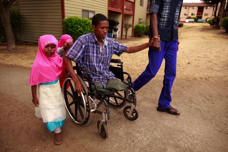 Mursal Jama travels through Kent’s Buena Casa apartments with his daughter Ilhan Hashi, 5, and friend Abubakar Ahmed. Jama, who lost his legs in a missile attack in Somalia, is attending ESL classes and aspires to work in computers, though a more pressing concern has been keeping up with the rent.  (Erika Schultz/The Seattle Times)