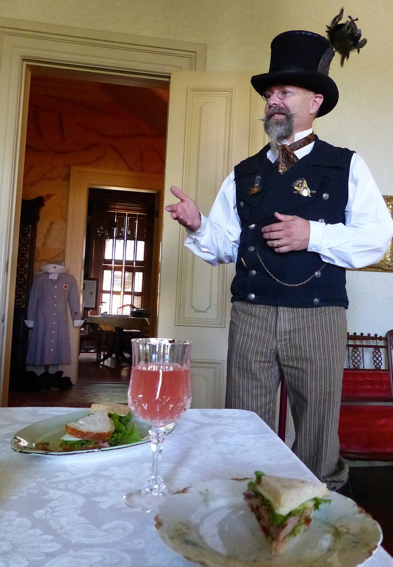 Museum guide Rick Tuttle, who frequently dons period costumes with a steampunk flair, tells history of the Kirkman House as steak sandwiches and grapefruit soda are served to Walla Walla Food Tours visitors. (Brian J. Cantwell/The Seattle Times)