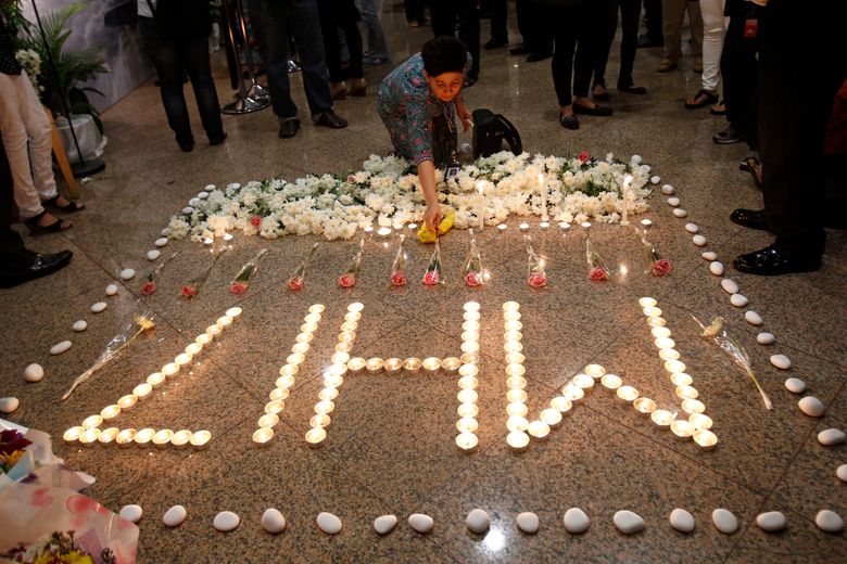 FILE – In this Friday, July 25, 2014 file photo, a Malaysia Airlines crew member places a flower next to candles forming the letters MH17 after a multi-faith prayers for the victims of the downed Malaysia Airlines Flight 17 at Malaysia Airlines Academy in Kelana Jaya, near Kuala Lumpur, Malaysia. The Dutch Safety Board is publishing its final report Tuesday, Oct. 13, 2015 into what caused Malaysia Airlines Flight 17 to break up high over Eastern Ukraine last year, killing all 298 people on board. (AP Photo/Lai Seng Sin, File)
