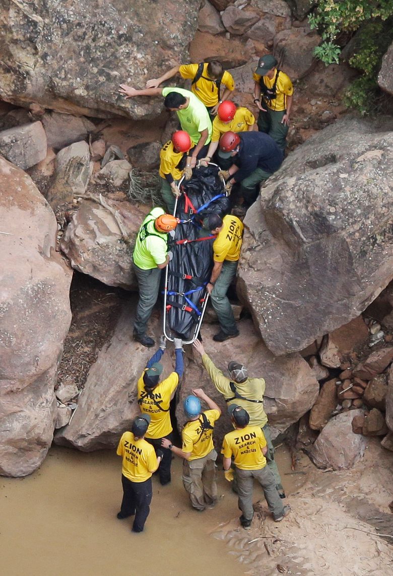 FILE – In this Sept. 16, 2015 file photo, search and rescue team members carry a body after it was found along Pine Creek, in Zion National Park, near Springdale, Utah.  Zion National Park officials are retracing what led up to the deaths of seven people in a flooded canyon on Sept. 15 before a panel assesses what can be done to keep a growing number of visitors safe when spectacular natural settings turn perilous. (AP Photo/Rick Bowmer, File)