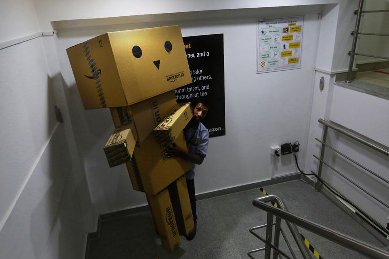 At the Amazon fulfillment center in Hyderabad, a worker relocates a Box Boy creation made from Amazon cartons. Each fulfillment center has a different one made by the local workers. (Alan Berner / The Seattle Times)