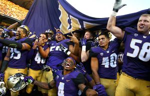 Washington players celebrate before a cheering crowd after beating WSU 45-10 at the 108th Apple Cup at Husky Stadium on Friday, November 27, 2015, in Seattle, Wash.