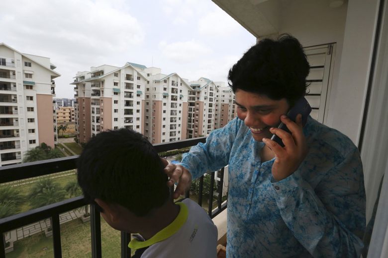 Many Indians return to be near family. Vasantha Gullapalli, on her balcony with son Abhiram, calls her sister Anita Chitturi Jagdeesh who lives across this gated complex in Hyderabad. Gullapalli returned with her husband, Sekhar Boddu, who works for Amazon.  (Alan Berner / The Seattle Times)