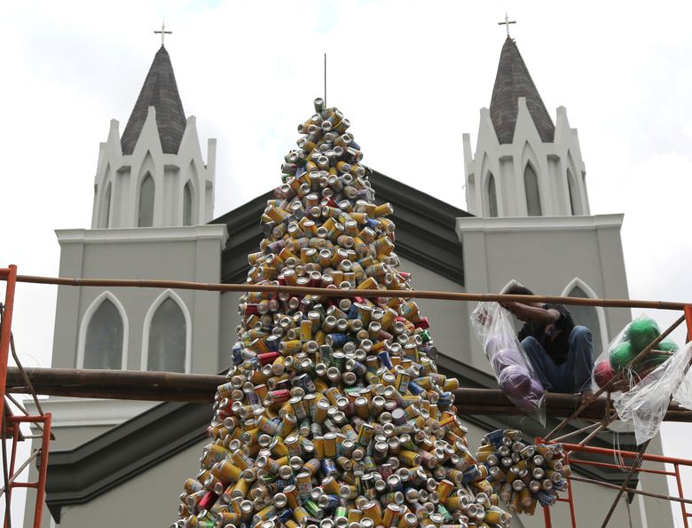 A worker arranges about ten thousand discarded beverage cans to form a Christmas tree in front of a church in Jakarta, Indonesia, Friday, Dec. 18, 2015. (AP Photo/Tatan Syuflana)
