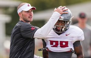 Washington State defensive coordinator Alex Grinch congratulates a player on his effort at fall camp in Lewiston.  The Washington State University Cougar football team practiced at Sacajawea Middle School in Lewiston, Idaho, Monday August 10, 2015.