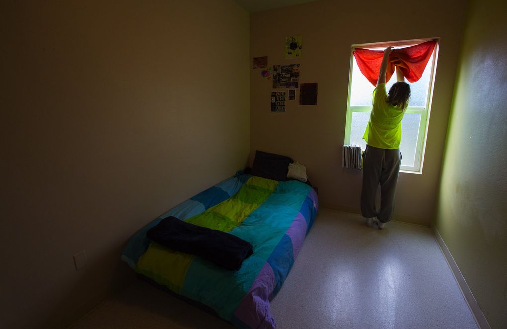 J. K. lets sunlight into her room at the Spruce Street Crisis Residential Center in Seattle. The state’s Becca laws created a network of secure facilities for runaways, but budget cuts have limited the resources to intervene with the teens. (Ellen M. Banner)