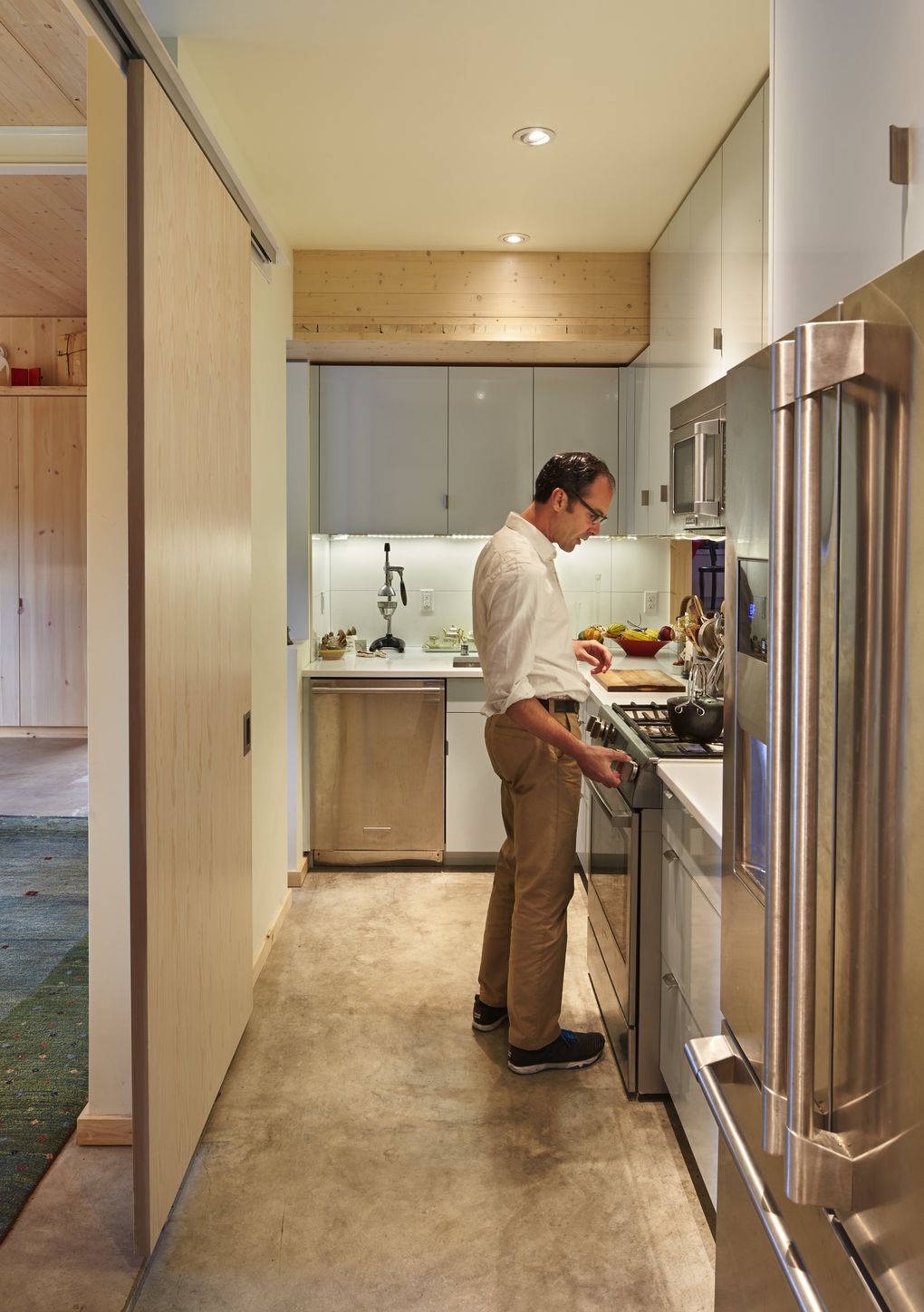 Marco Zangari cooks in the home’s galley kitchen, with its cool, utilitarian concrete floor and quartz-finished countertops. All the appliances, except the stove, were upcycled from the site’s previous home. (Benjamin Benschneider/The Seattle Times)