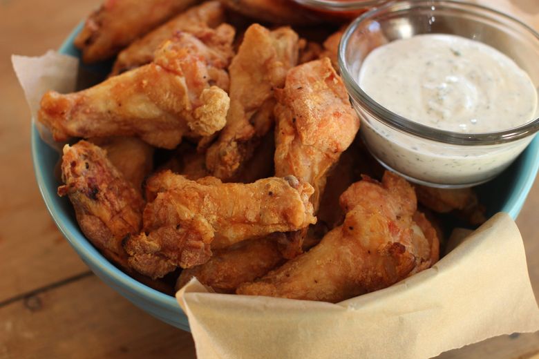 Party wings are served with cilantro sour cream dip and honey sriracha. (Matthew Mead/The Associated Press)