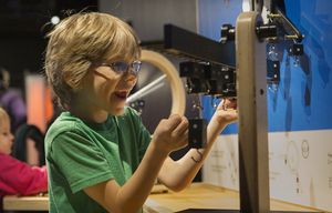 Isaac Wade, 7, seems thrilled when the weight he placed on the balance beam makes the beam level.  He was there with family and his sister, Rachel, 2 (at left).  They live in Auburn.  Pacific Science Center’s  new exbibit “Math Moves,” which opens Saturday, January 23, 2016, consists of an  interactive set of displays that involves experiencing ratio and proportion and helps kids get comfortable with learning about math.