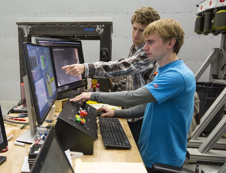 Lead process engineer Chris Kingsley, front, and control engineer Kyle Walker work the controls for the Automated Fiber Placement machine making 777X test wing spars. (Mike Siegel/The Seattle Times)