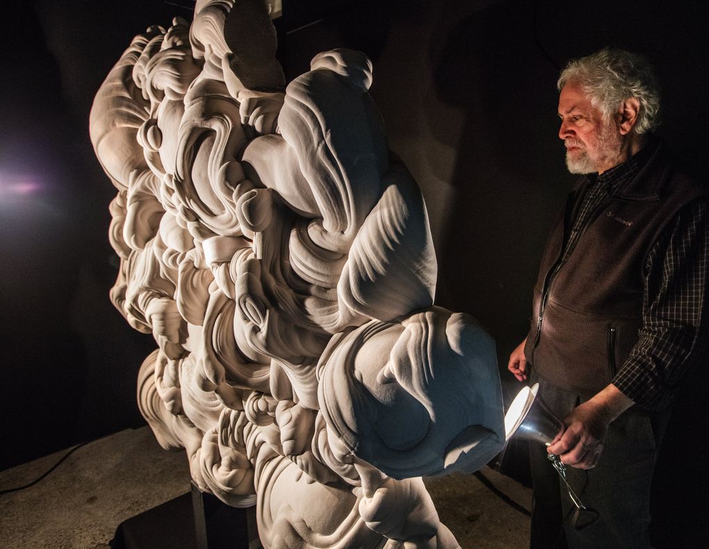 Richard Berger holds a light to the back of a Fontainebleau sandstone concretion, one of many he has in the collection. (Steve Ringman / The Seattle Times)