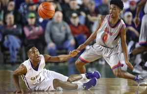 Garfield point guard Jashaun Agosto looks up at the ball after losing his footing while driving against Rainier Beach guard Kahlil Shabazz during the second half in a Boys 3A semifinal game during the Hardwood Classic tournament at the Tacoma Dome on Friday, March 4, 2016. The Hardwood Classic concludes with the state title games on Saturday.