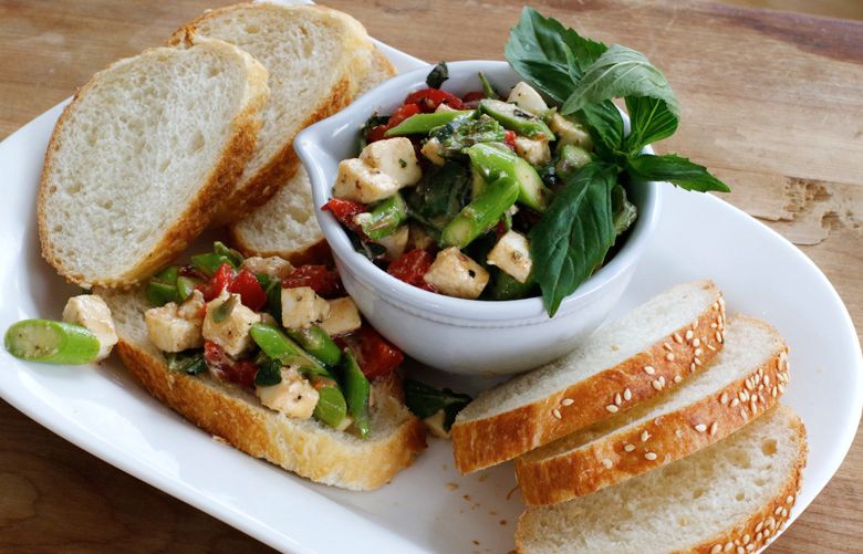 This March 7, 2016 photo shows asparagus bruschetta served on sliced baguette in Concord, N.H. The bruschetta combines thinly sliced raw asparagus with chopped roasted red peppers, fresh mozzarella and torn basil. (AP Photo/J.M. Hirsch)