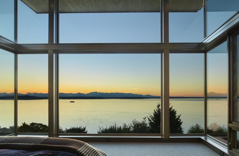 Upstairs, the master bedroom cantilevers spectacularly toward Puget Sound. Nearly 12-foot-tall walls of glass wrap the room on three sides. “Clearly the view is a huge component,” Finne says. “All major spaces open to sweeping views. As soon as we framed the master, everyone was, ‘Oh, my God.’ ”  (Benjamin Benschneider/The Seattle Times)
