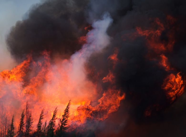 Wildfires, like this one burning on Highway 63 in Alberta, Canada, spread to the main oil-sands facilities north of Fort McMurray, knocking out 1 million barrels of production from Canada’s energy hub.  (Darryl Dyck/Bloomberg)
