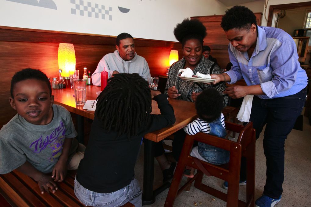 General manager Erika White brings out plates to Steve Monroe; his daughter Lakisha Monroe; and her children Josiah Walters, 7, gray shirt; Joshua Walters, 5, black shirt; and Jahara Walters, 8 months, at Fat’s Chicken and Waffles in the Central District. (Erika Schultz/The Seattle Times)