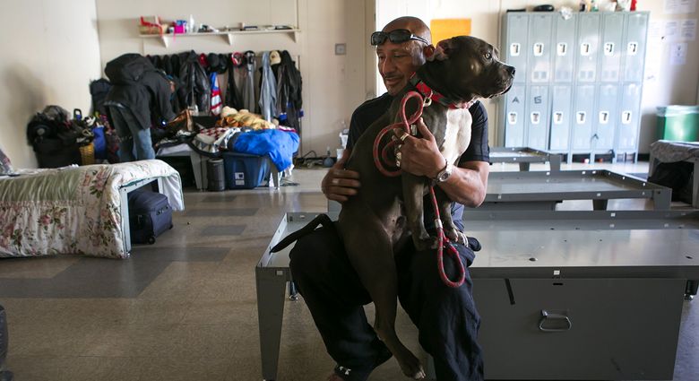 Michael, 54, holds RJ, a neighbor’s pit bull, at the Navigation Center, a low-barrier homeless shelter in the Mission District of San Francisco. The Navigation Center allows clients to bring in what they call “the three P’s” — possessions, pets and partners.  (Bettina Hansen/The Seattle Times)
