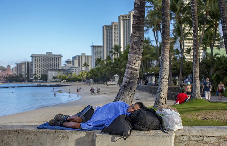A homeless man sleeps near a pier on Waikiki Beach in Honolulu, March 7, 2016. Responding to what the governor of Hawaii has called a state of emergency, Honolulu has passed tough criminal laws aimed at ridding sidewalks, streets and parks of the homeless. (Monica Almeida/The New York Times)