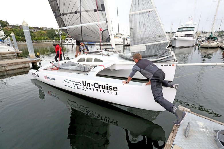 Dan Blanchard’s trimaran “Unscrewed” moves away from the guest dock at Shilshole Bay Marina on Friday for a test run. Crew member Graeme Esarey, right, gives the boat a shove. Esarey was part of a crew that won the inaugural Race to Alaska and $10,000 in 2015. This year’s race starts Thursday. (Greg Gilbert/The Seattle Times)