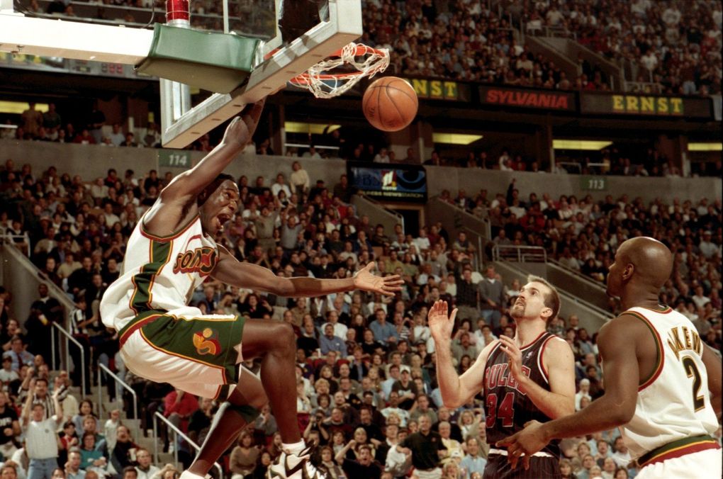 Sonics forward Shawn Kemp dunks after snatching a pass above the rim from Gary Payton in a game against the Chicago Bulls. (Mark Harrison/The Seattle Times)