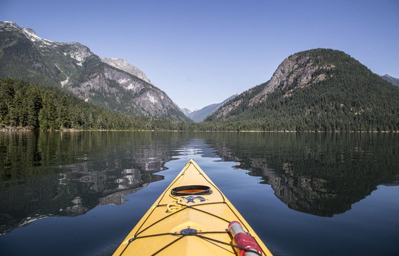 Kayaking on Ross Lake between the shadows of an unidentified peak at left and Pumpkin Mountain at right. In the saddle between is the Big Beaver Creek trail in the North Cascades National Park. (Steve Ringman / The Seattle Times)